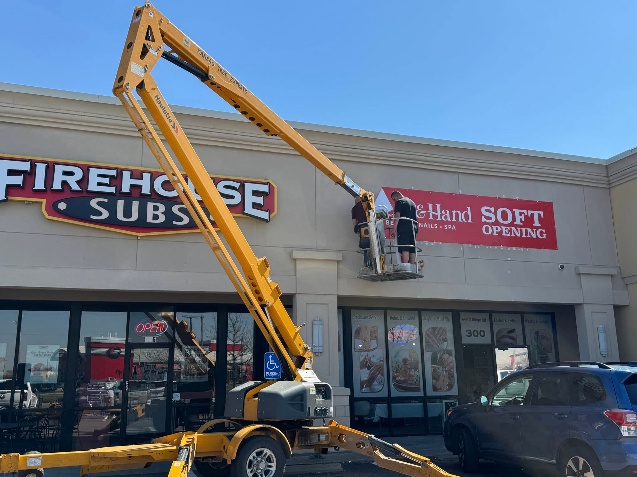 Wichita Wrap Co crew hanging a business sign from a lift